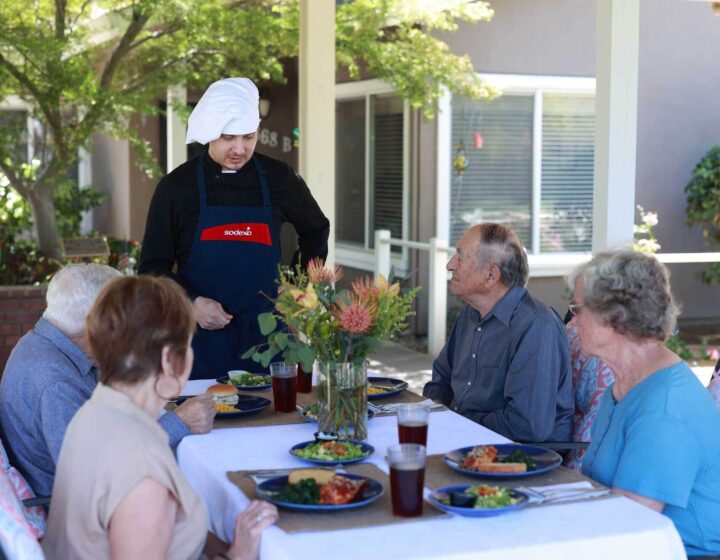 Bethany residents dining outdoors while talking to the chef